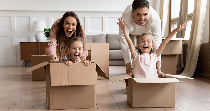 Excited family having fun on moving day riding in boxes