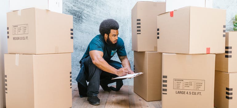 One of interstate movers in Maryland writing next to many boxes.