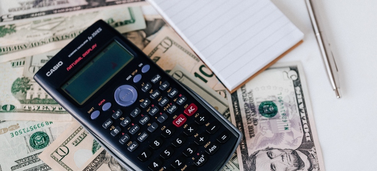 Calculator, pen, notepad, and money on a table