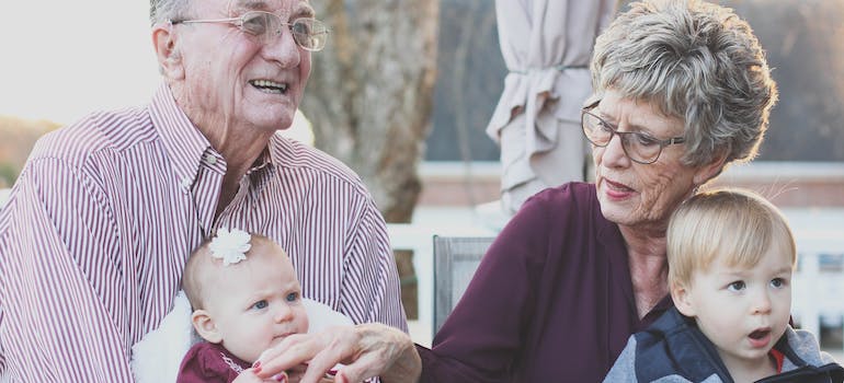 elderly couple holding their grandchildren talking about the senior's guide to a stress-free moving day