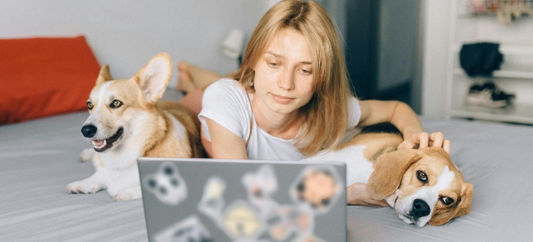 Woman reading how to pet-proof your new home on a bed with two dogs 