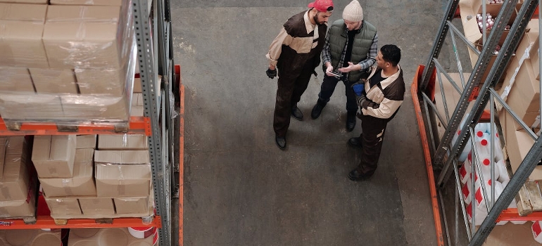 Men standing in a warehouse talking about warehouse management systems. 