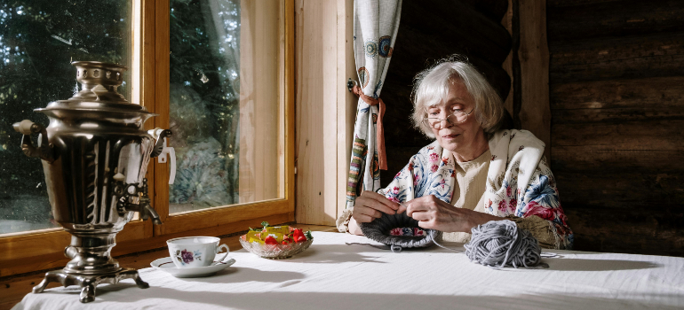 elderly woman knitting in her new home with post move tips for seniors to feel at home