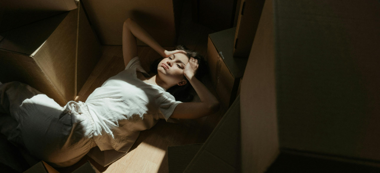 a woman lying in between the boxes holding her head 