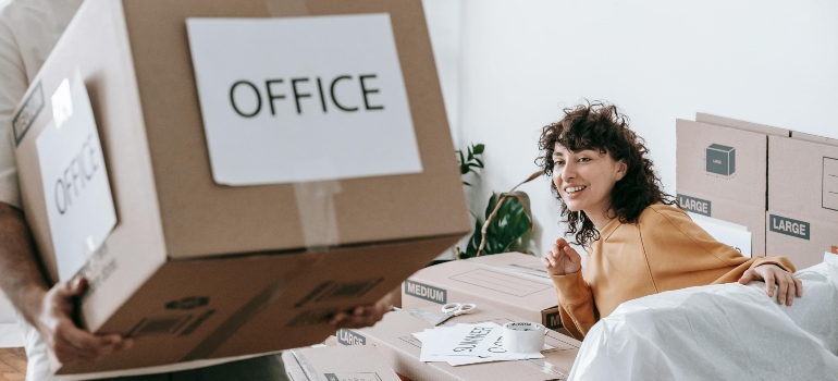 A man carrying a box with the words "OFFICE" written on it. 