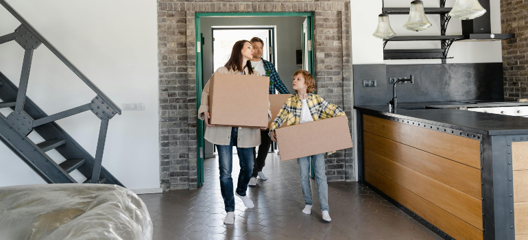 family carrying boxes into a new home