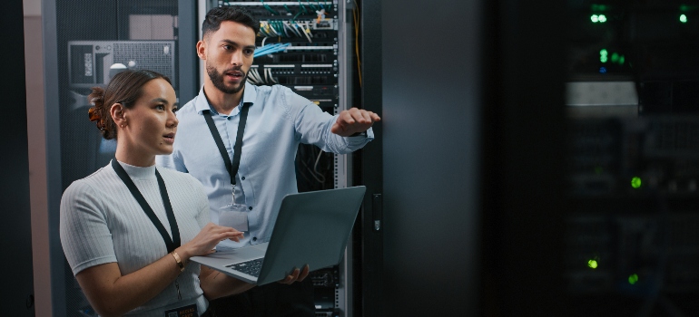 Two IT professionals discussing and working in a server room