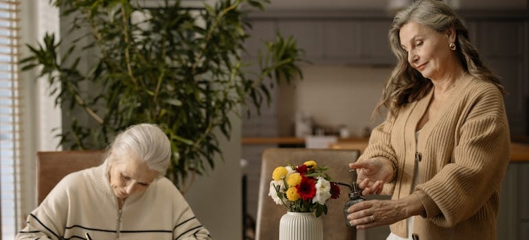 Two elderly ladies in the dining room talking about moving aging parents to another state