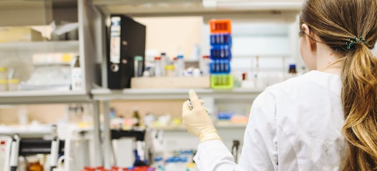 woman in white laboratory gown thinking about minimizing downtime in laboratory relocations