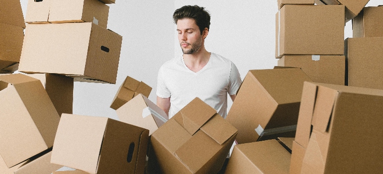 a man surrounded by boxes following essential packing tips for an efficient move