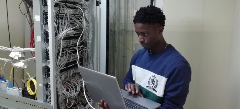 IT technician with laptop inspecting servers, illustrating a data center relocation risk management plan.