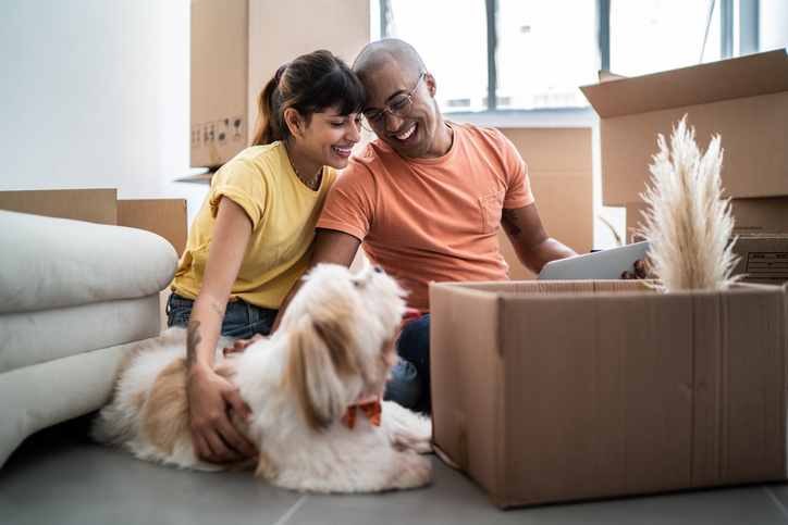 young couple with dog in living room with moving boxes